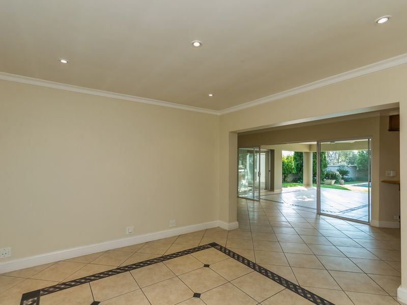 Spacious open-plan living area featuring tiled floors with decorative inlay, recessed lighting, and large sliding doors providing seamless access to the outdoor patio.