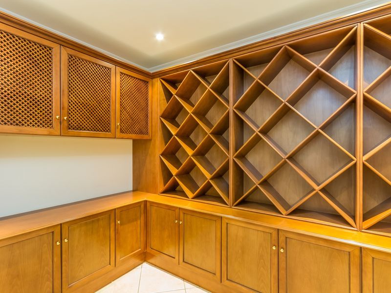 A dedicated wine cellar featuring extensive custom-built wooden cabinetry with integrated lattice wine storage racks and recessed lighting.