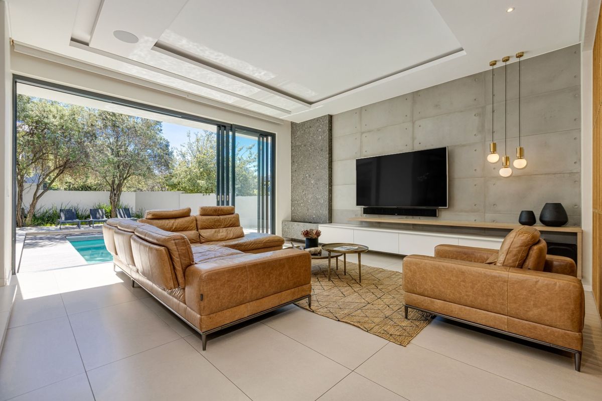 Modern living room featuring a concrete feature wall, recessed ceiling, and large sliding glass doors that open directly to the pool area.