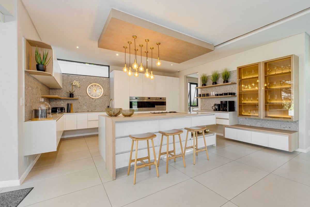 Modern, high-end kitchen featuring a central island, integrated appliances, stone splashbacks, and custom cabinetry with elegant pendant lighting.