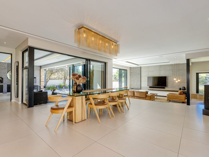 Spacious open-plan living and dining area featuring large format floor tiles, an exposed concrete feature wall, built-in fireplace, and seamless indoor-outdoor flow.