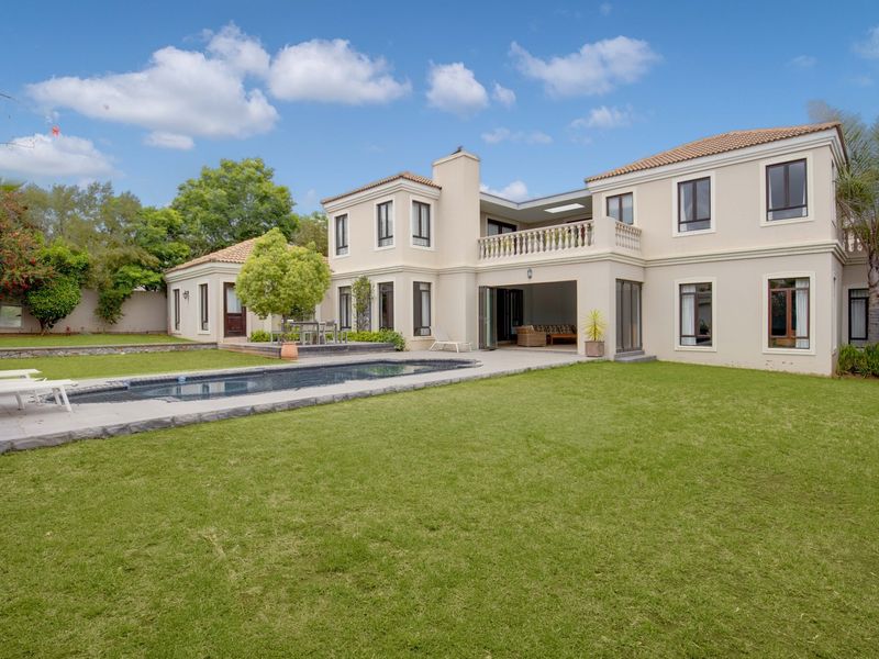 Spacious rear exterior view featuring a well-maintained lawn, swimming pool, and a two-story residence with a balcony and terrace area.