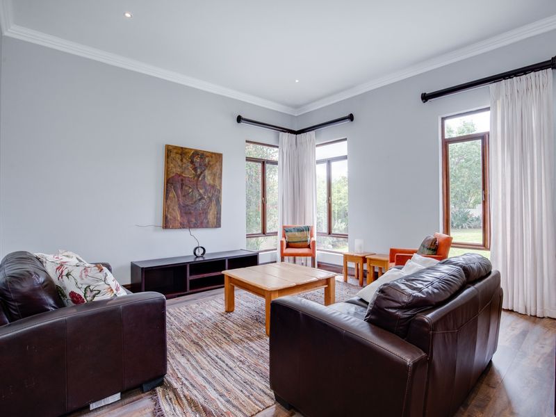 A bright and spacious living room featuring timber-framed windows, elegant cornicing, and recessed downlighting, offering a comfortable and well-maintained living environment.