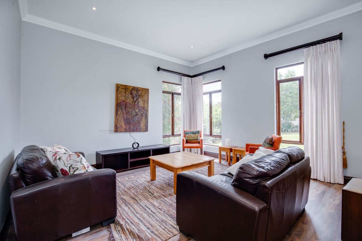 A bright and spacious living room featuring timber-framed windows, elegant cornicing, and recessed downlighting, offering a comfortable and well-maintained living environment.