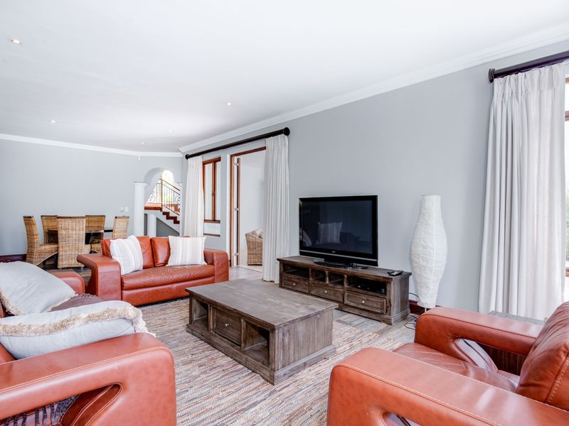 Spacious open-plan living and dining area featuring neutral walls, recessed lighting, and direct access to an adjoining staircase and outdoor space.