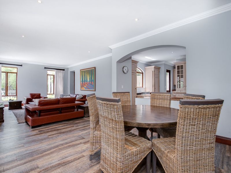 Spacious open-plan living and dining area featuring wood-look flooring, recessed lighting, and an elegant archway leading to the kitchen.