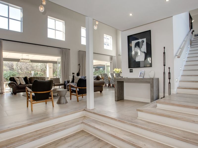 Spacious open-plan living area featuring a sunken lounge, elegant staircase, high ceilings, and large windows that provide abundant natural light and garden access.