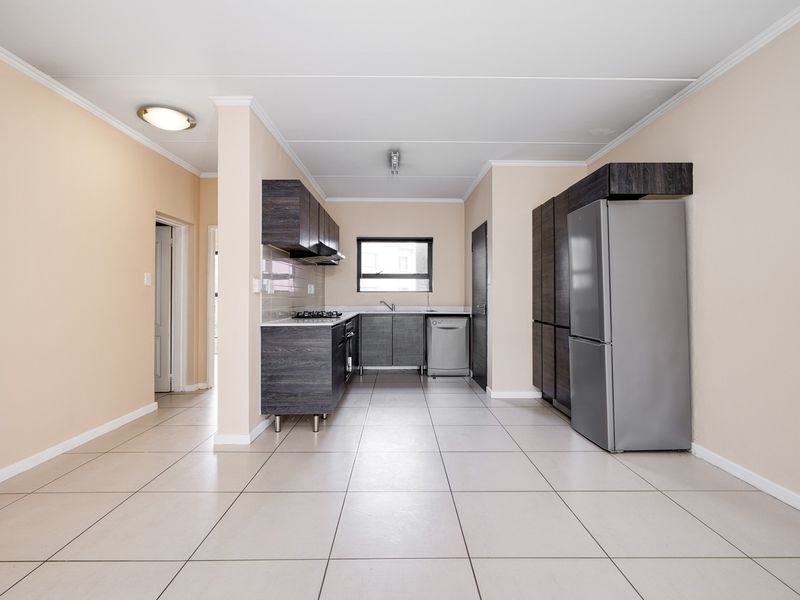 A clean, functional kitchen featuring dark wood cabinetry, tiled flooring, and built-in appliances, offering a neutral and well-maintained space.