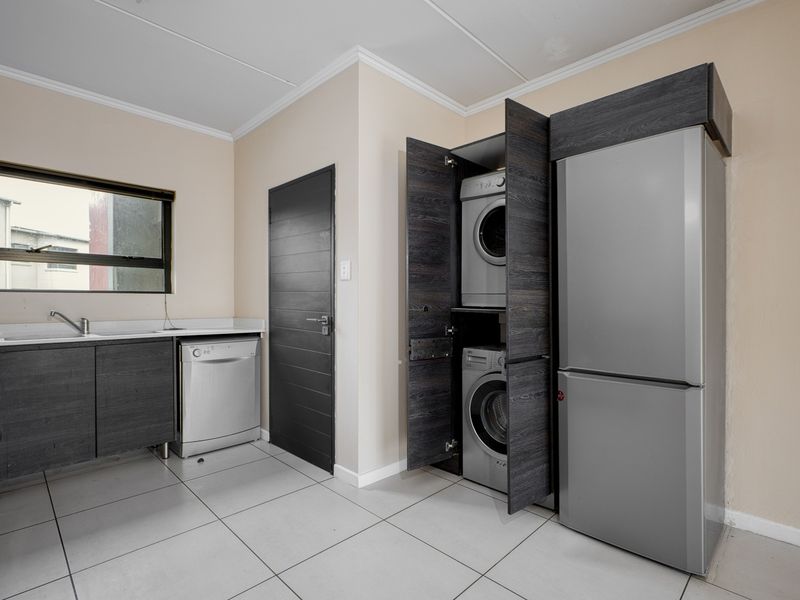 A functional laundry area featuring built-in cabinetry, tiled flooring, and a dedicated cupboard for laundry appliances.