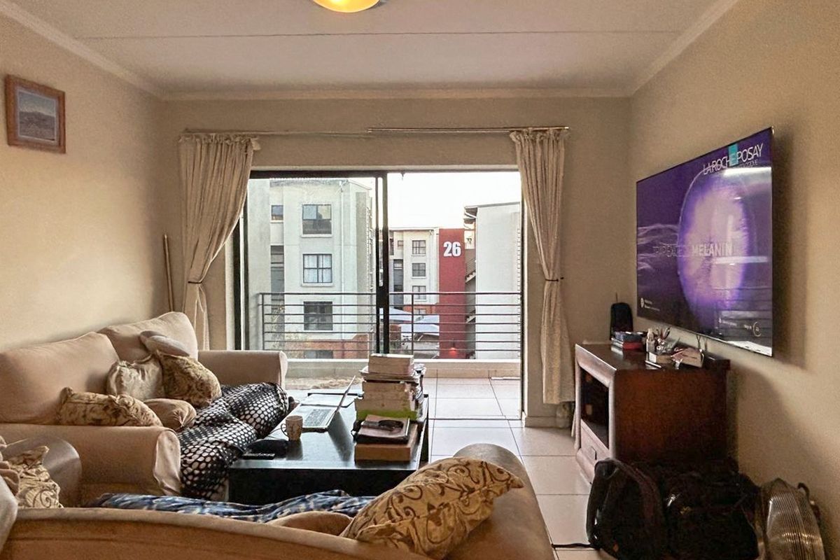 A living room featuring tiled flooring and a sliding glass door that opens onto a balcony, providing natural light and an urban view.