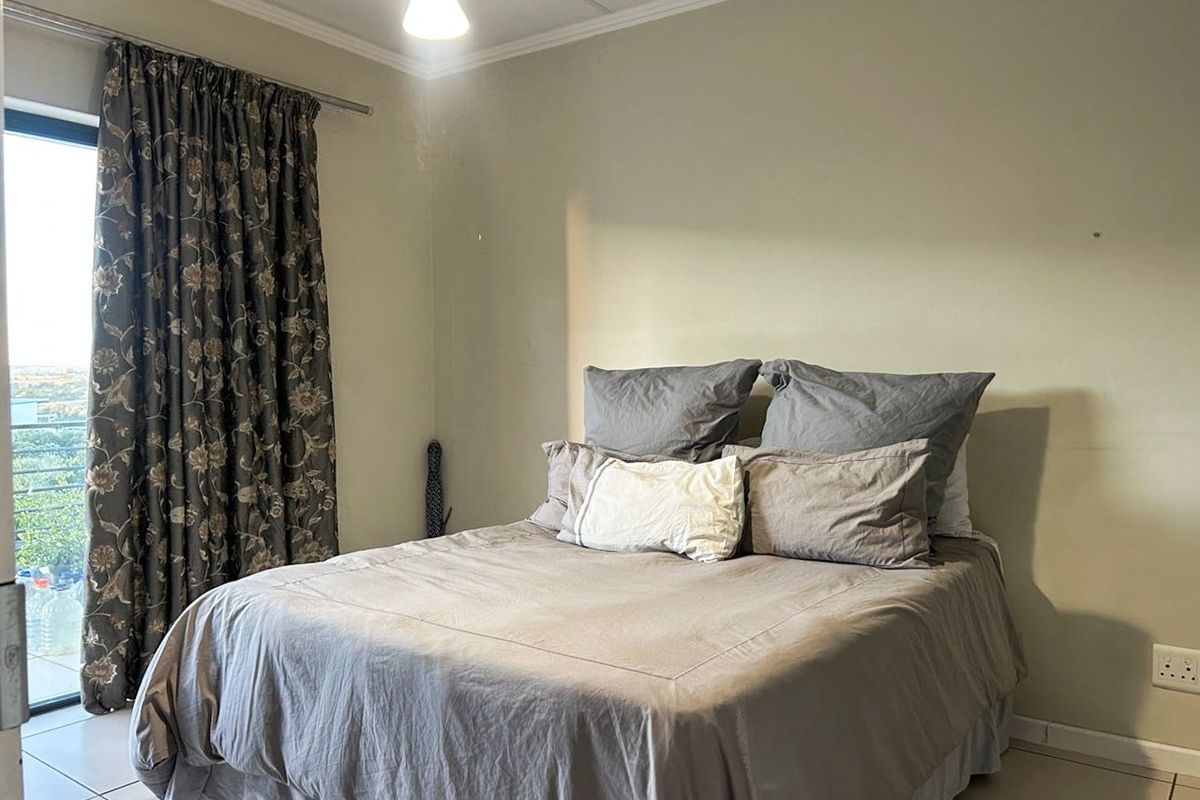 A functional bedroom featuring tiled flooring and a sliding glass door providing natural light and access to an outdoor area.