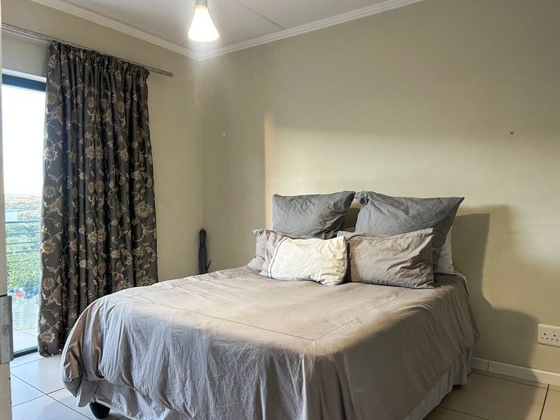 A functional bedroom featuring tiled flooring and a sliding glass door providing natural light and access to an outdoor area.