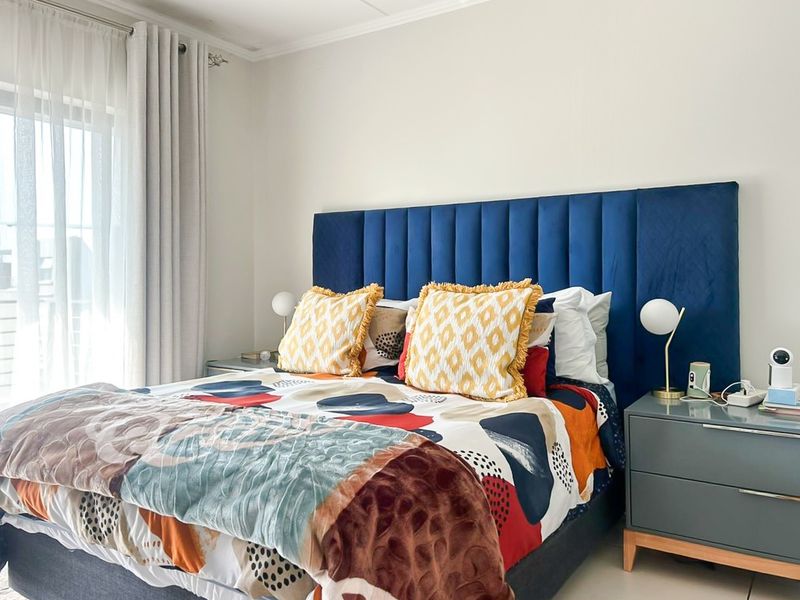 A well-maintained bedroom featuring neutral walls, tiled flooring, and a large sliding glass door providing natural light.