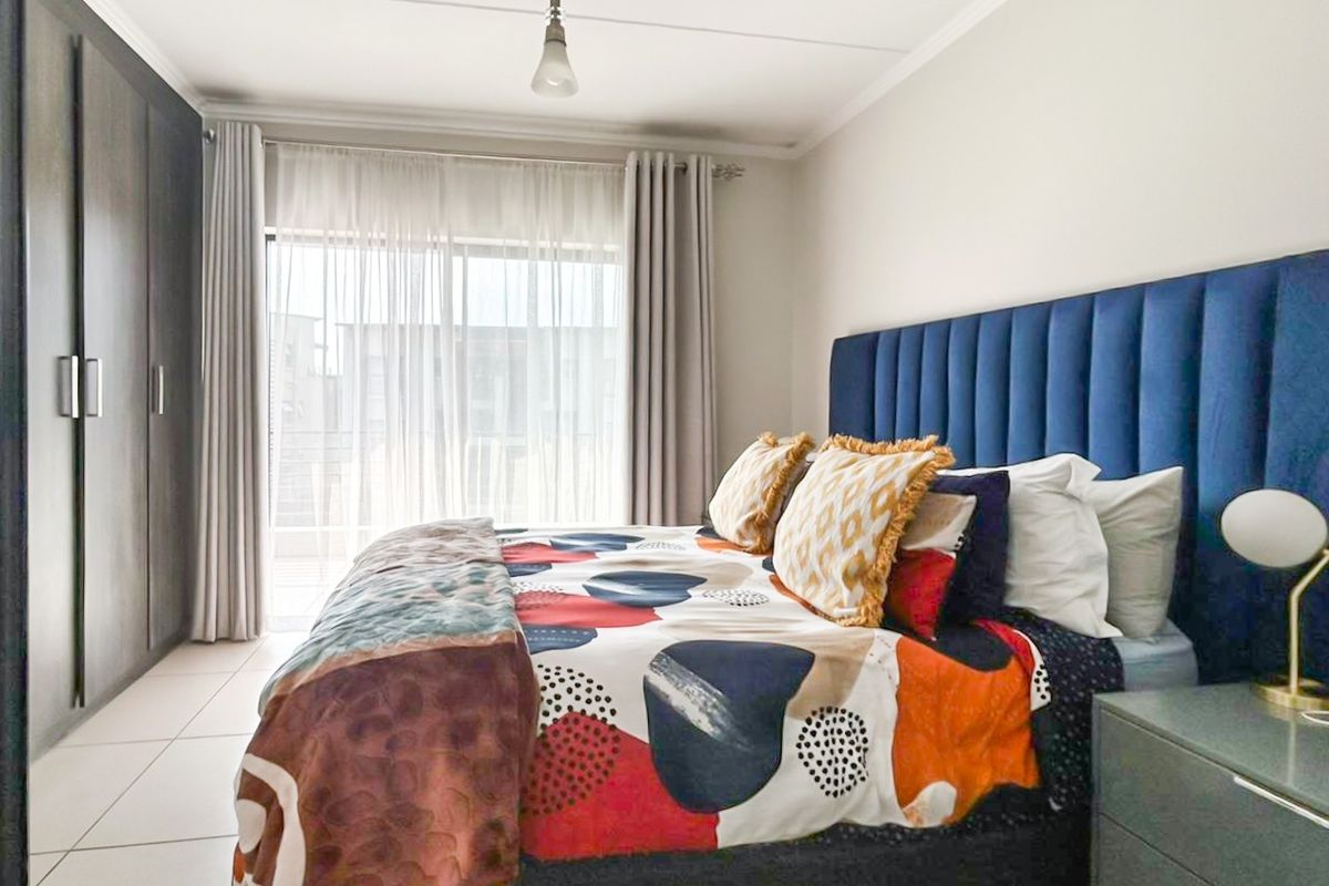 A well-maintained bedroom featuring built-in cupboards, tiled flooring, and a sliding glass door providing access to an outdoor area.