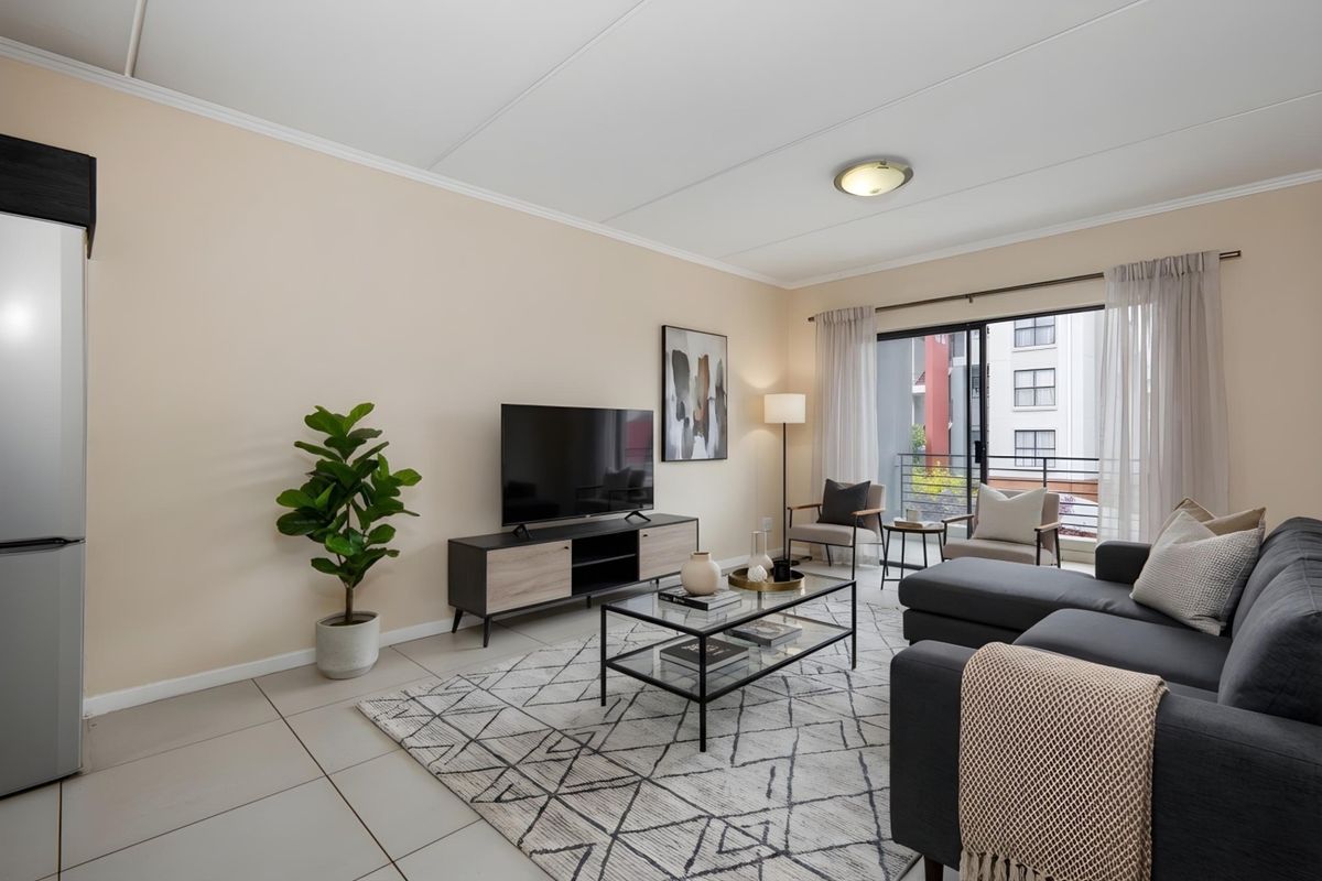 A bright and well-maintained living room featuring tiled flooring and a large sliding glass door that provides access to a balcony.