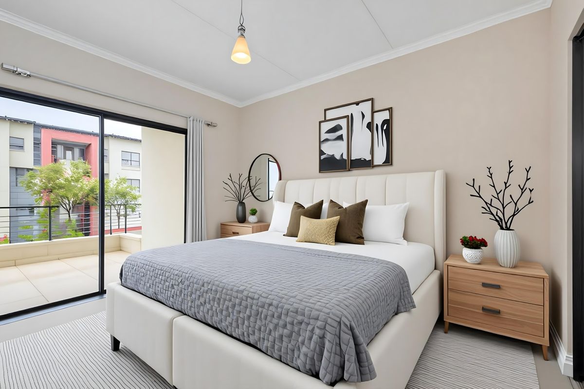A well-maintained bedroom featuring neutral walls, cove molding, and a large sliding glass door providing direct access to a private balcony.