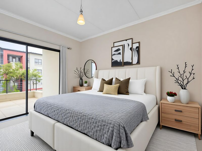 A well-maintained bedroom featuring neutral walls, cove molding, and a large sliding glass door providing direct access to a private balcony.