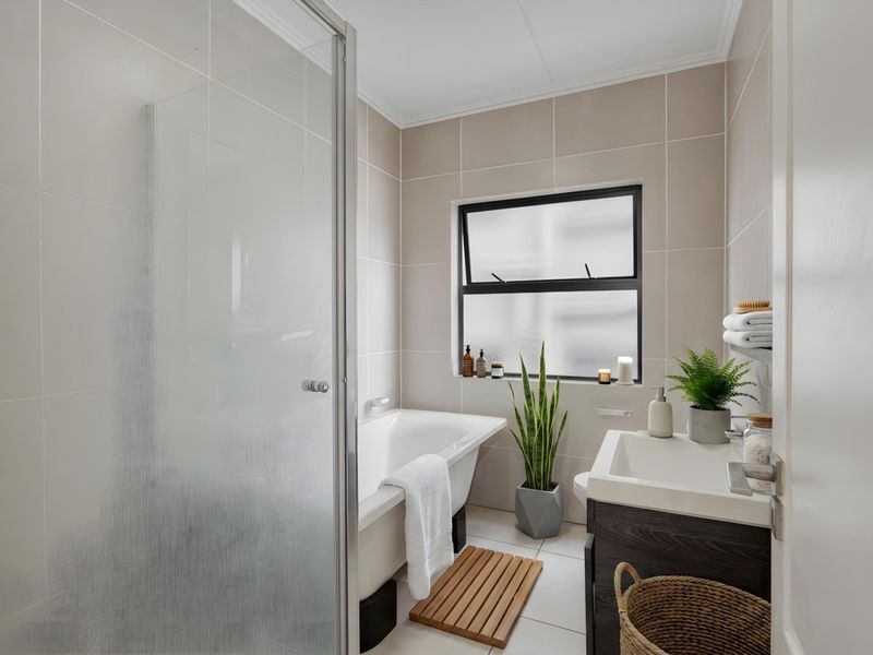 A modern, well-maintained bathroom featuring a shower enclosure, a bathtub, and a vanity cabinet with a basin, finished with neutral wall and floor tiles.