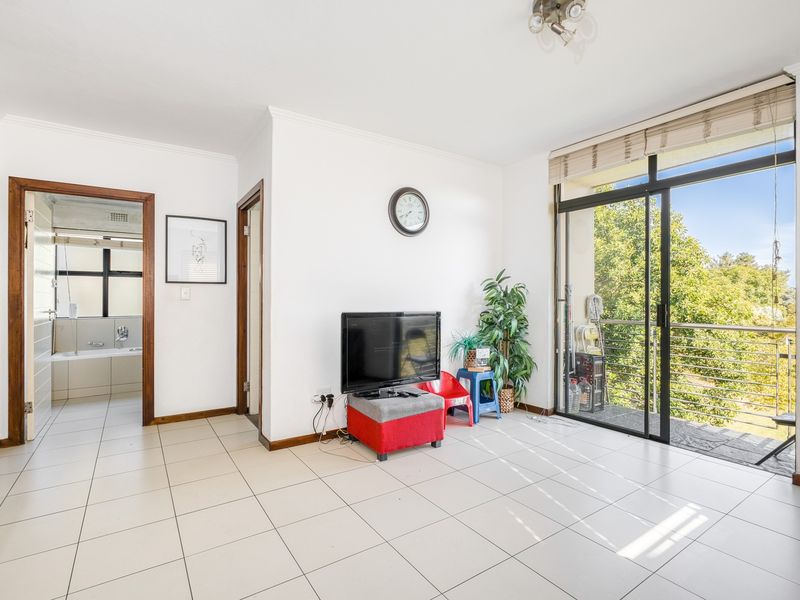 A bright living room featuring tiled flooring, coving, and large sliding glass doors providing access to an outdoor balcony area.