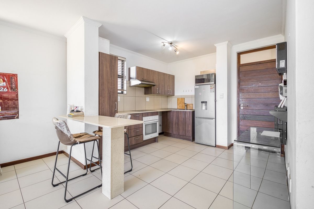 A functional kitchen featuring wood-finish cabinetry, stone countertops, a breakfast bar, and tiled flooring, providing a practical layout for daily use.