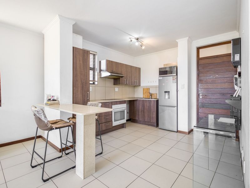 A functional kitchen featuring wood-finish cabinetry, stone countertops, a breakfast bar, and tiled flooring, providing a practical layout for daily use.