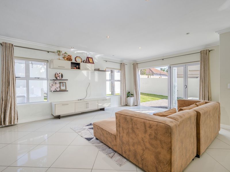 Bright and spacious living room featuring polished tiled floors, recessed lighting, and large sliding glass doors providing seamless access to the rear garden.