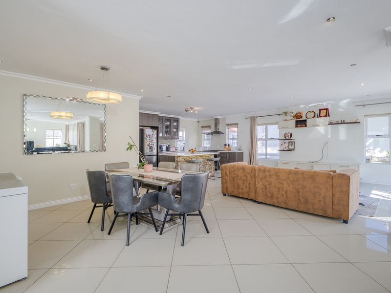 Spacious open-plan living and dining area featuring large format floor tiles, recessed lighting, and a modern kitchen with a central island.