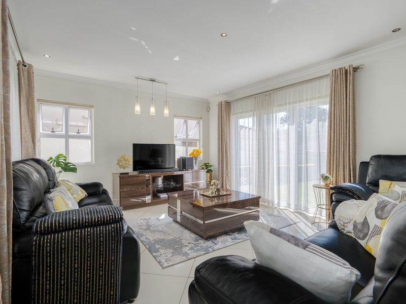 A bright and well-maintained living room featuring tiled flooring, recessed downlights, and large sliding glass doors that provide access to the outdoor area.