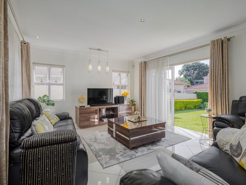 Bright and spacious living room featuring tiled floors, recessed lighting, and large sliding glass doors providing seamless access to the rear garden.