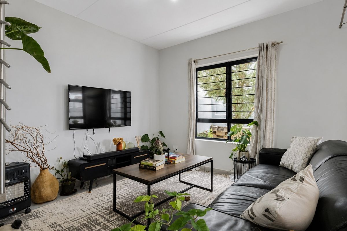 A well-lit living room featuring a large window with security bars, neutral walls, and modern finishes.