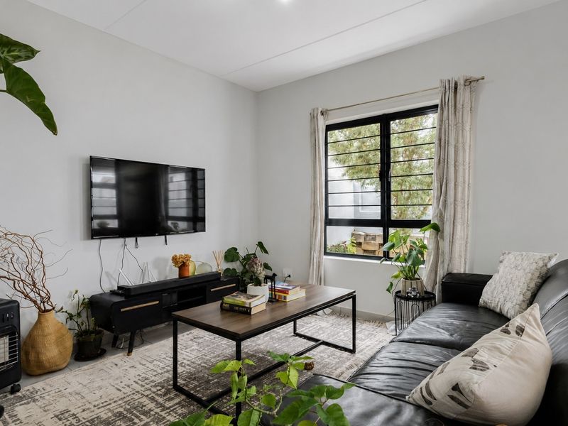 A well-lit living room featuring a large window with security bars, neutral walls, and modern finishes.