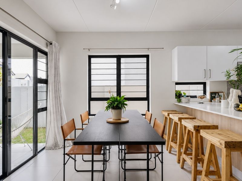 Modern open-plan dining and kitchen area featuring sleek cabinetry, a breakfast bar, and large sliding doors opening to a private patio.