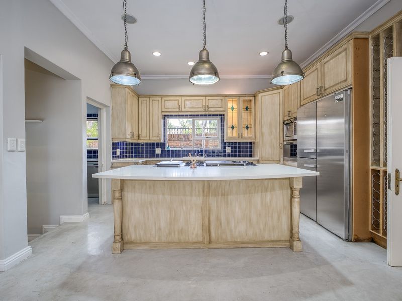 Spacious kitchen featuring a central island, stainless steel appliances, ample cabinetry, and a tiled backsplash, offering a functional layout with potential for cosmetic updates.
