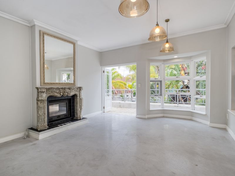 Spacious living room featuring polished concrete floors, an ornate fireplace, bay windows, and direct access to an outdoor balcony area.