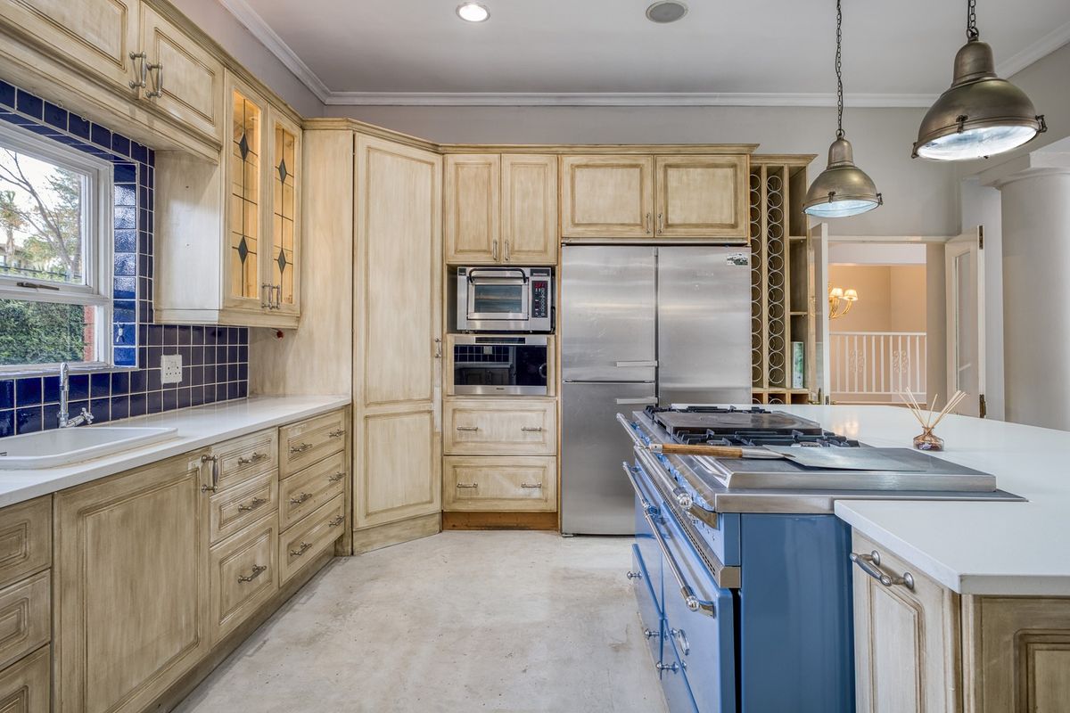 Spacious kitchen featuring custom cabinetry, a large blue range cooker, integrated appliances, and a central island with ample counter space.