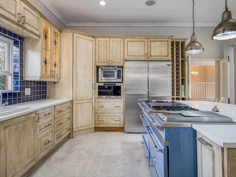 Spacious kitchen featuring custom cabinetry, a large blue range cooker, integrated appliances, and a central island with ample counter space.