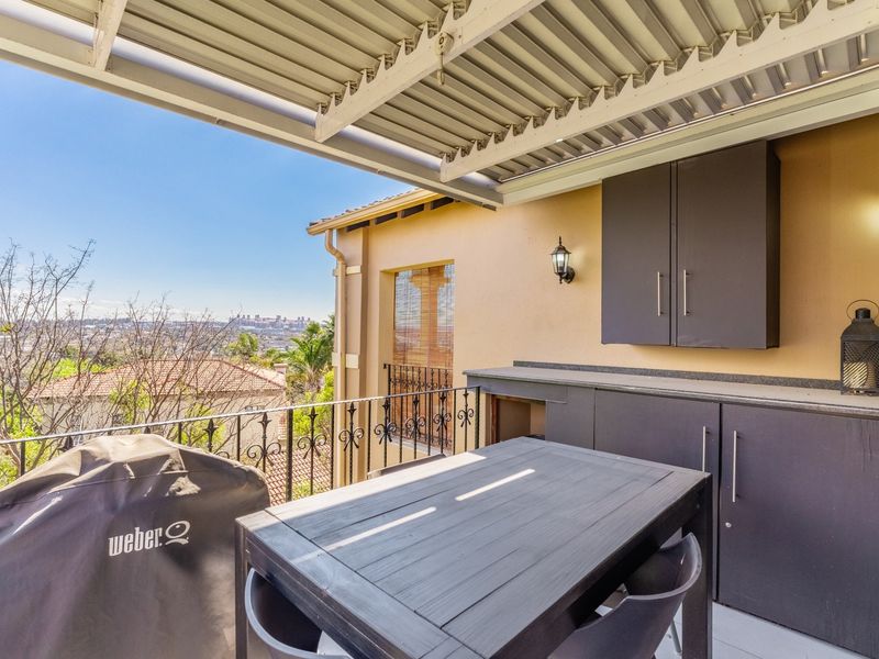 Covered balcony featuring built-in cabinetry, wrought iron railings, and elevated views of the surrounding area.