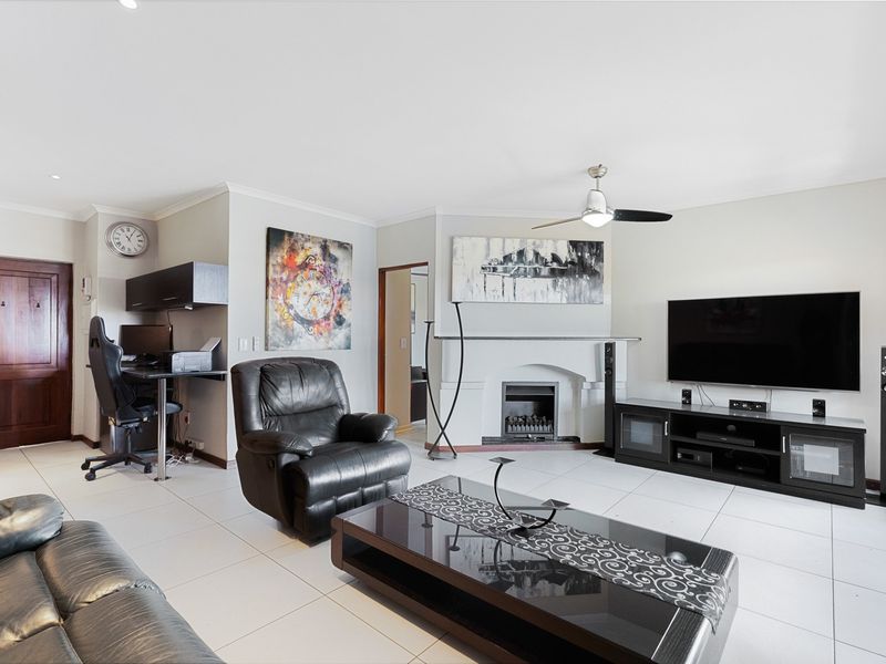 Spacious living room featuring tiled flooring, a central fireplace, and a ceiling fan, providing a comfortable and functional open-plan living area.