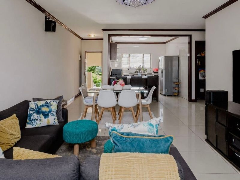 Spacious open-plan living and dining area featuring neutral tiled flooring, crown molding, and a seamless transition into the functional kitchen space.