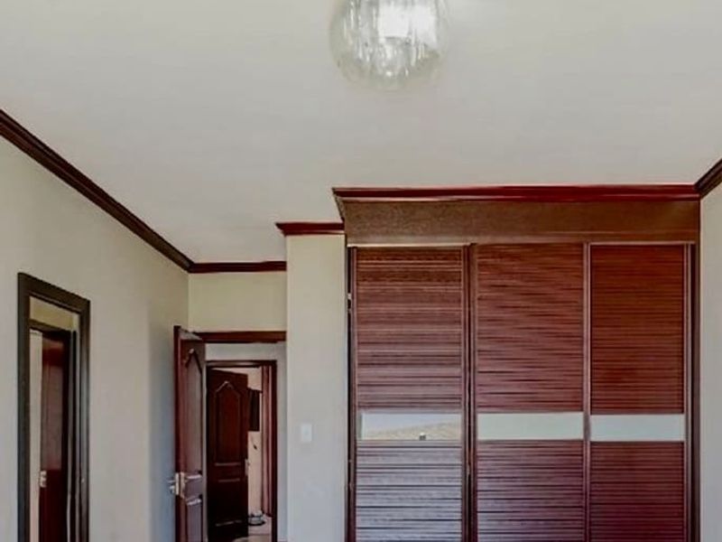 A bedroom featuring dark wood built-in wardrobes, matching crown molding, and a central ceiling light fixture.
