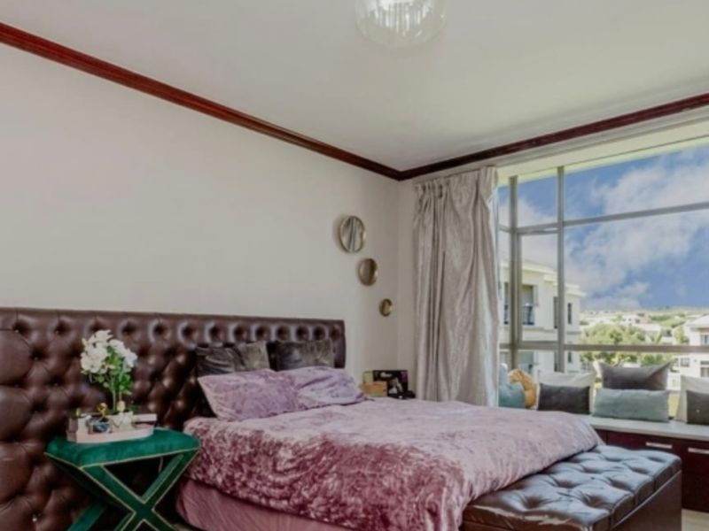 A well-maintained bedroom featuring laminate flooring, crown molding, and a large window with a built-in window seat offering natural light.