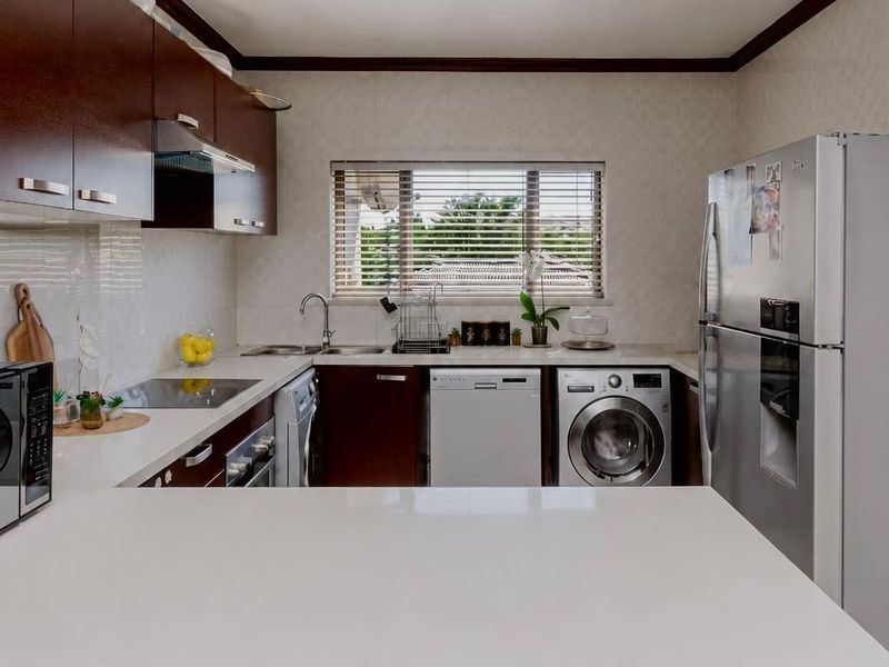 A well-maintained kitchen featuring dark wood cabinetry, stone countertops, and integrated appliances, offering a functional and clean workspace.