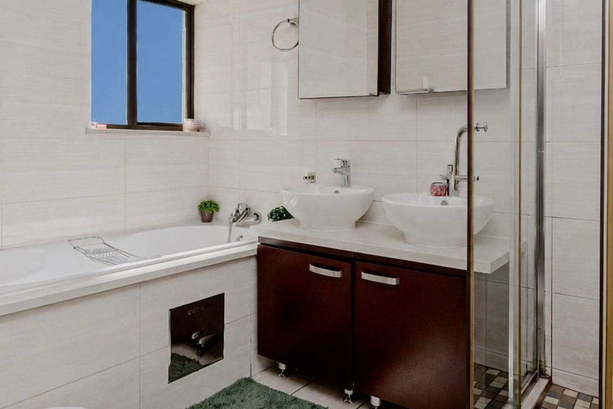 Modern bathroom featuring a double vanity with vessel sinks, a built-in bathtub, and a separate glass-enclosed shower with tiled flooring.