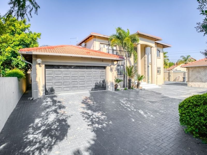 Front elevation of a double-story house featuring a paved driveway, double garage, and a covered entrance with architectural columns.