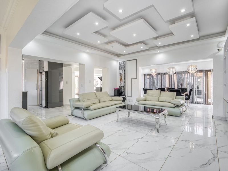 Spacious open-plan living and dining area featuring modern recessed ceiling lighting, high-gloss marble-look floor tiles, and seamless flow to the kitchen and outdoor space.