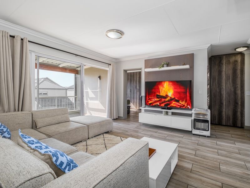 A well-maintained living room featuring tiled flooring, built-in cabinetry, and a sliding glass door leading to an outdoor balcony area.