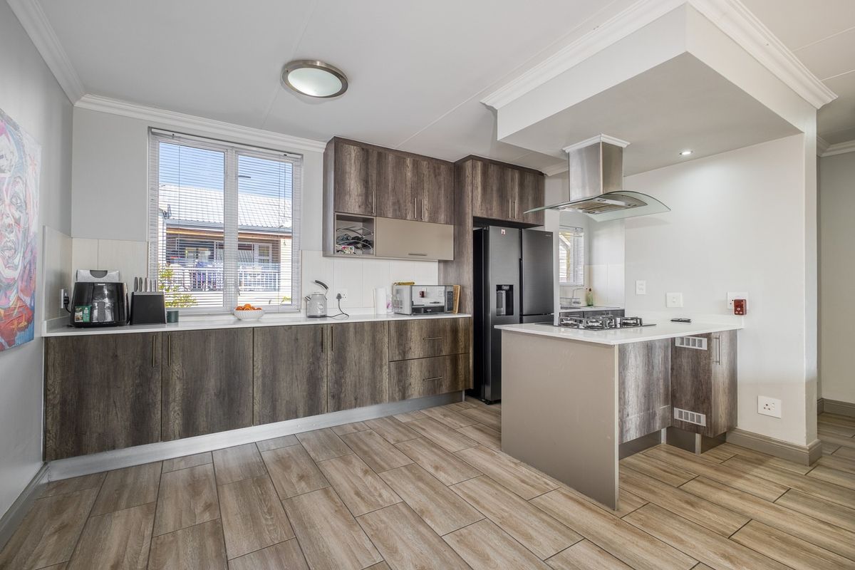 Modern kitchen featuring wood-grain cabinetry, stone countertops, a central island with a gas hob, and an integrated extractor fan.