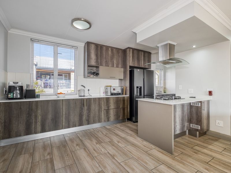 Modern kitchen featuring wood-grain cabinetry, stone countertops, a central island with a gas hob, and an integrated extractor fan.