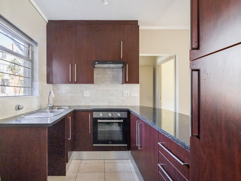 A functional kitchen featuring dark wood cabinetry, granite countertops, a built-in oven, extractor fan, and tiled backsplash.