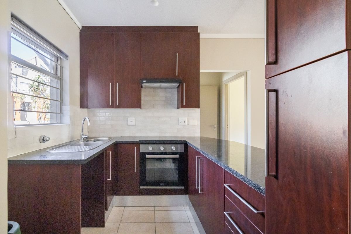 A functional kitchen featuring dark wood cabinetry, granite countertops, a built-in oven, extractor fan, and tiled backsplash.